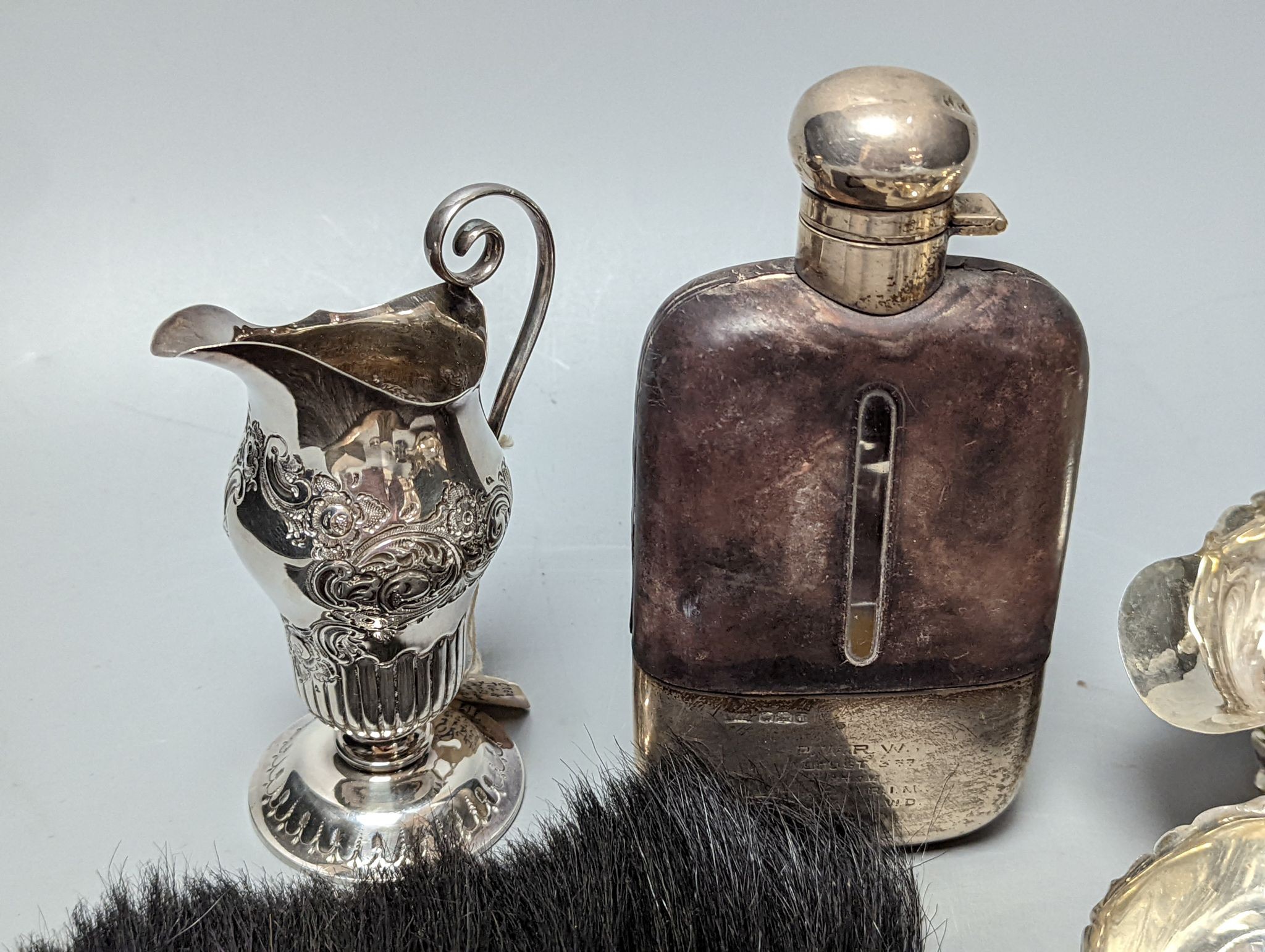 A group of assorted silver items including George V silver mounted hip flask(bruise), a pair of silver sauceboats(a.f.) one other sauceboat, sterling box, two silver cream jugs, cigarette box, salt, sugar tongs, brush an